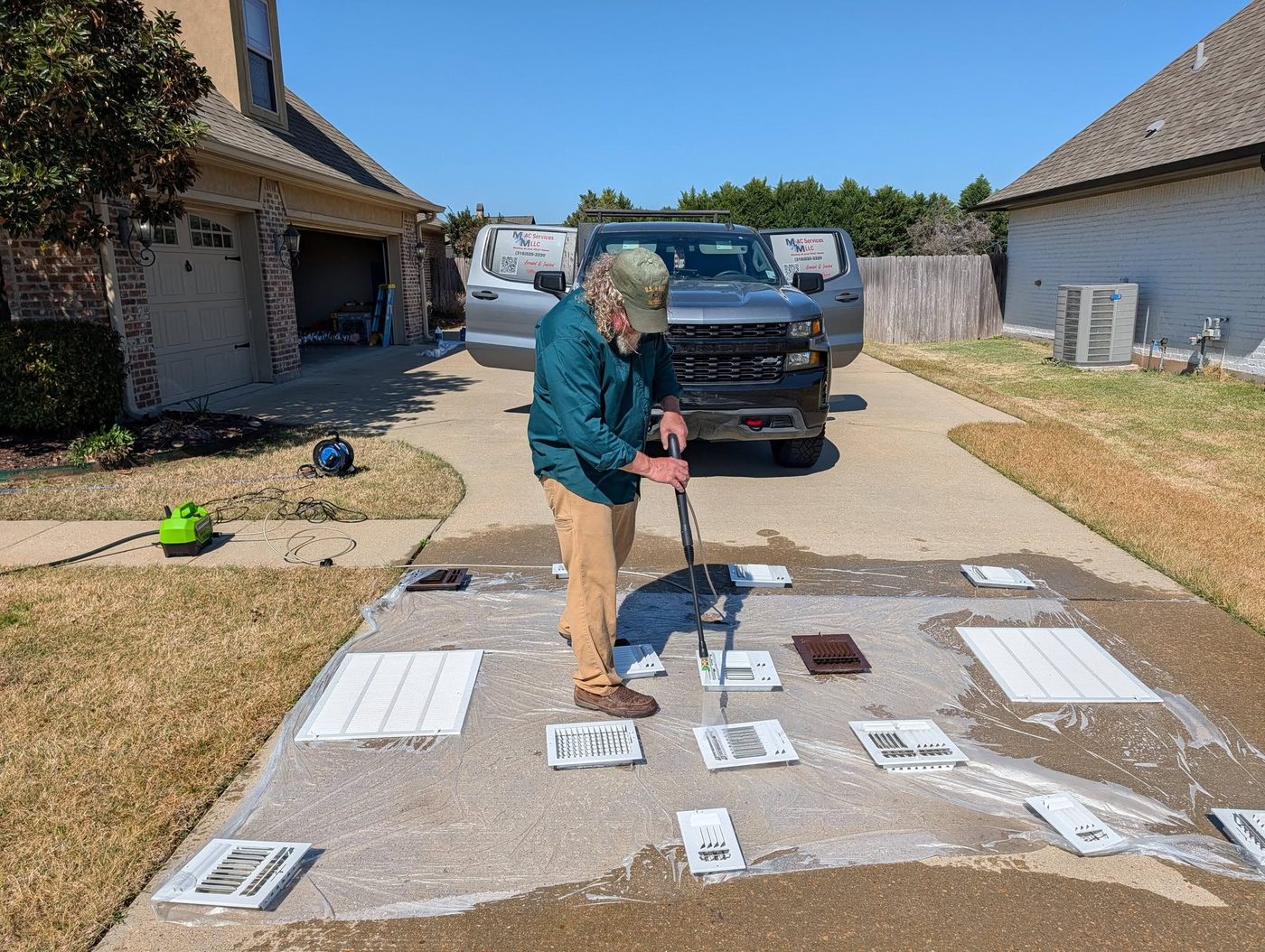 M-n-M technician cleaning air vent covers beside the company service truck
