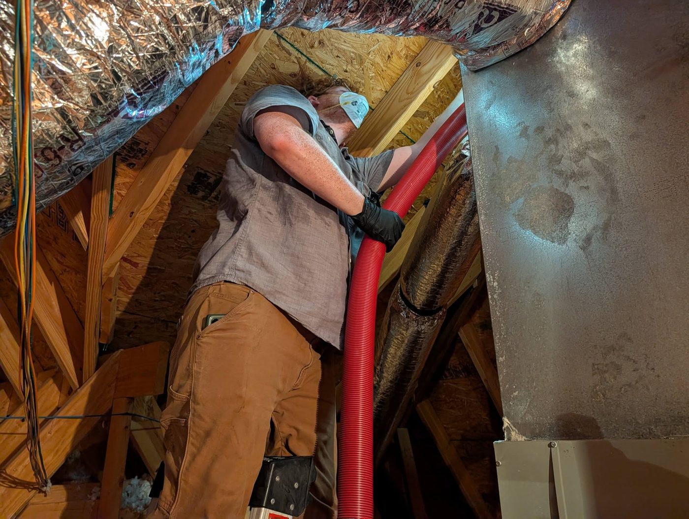 M-n-M technician servicing ductwork in an attic